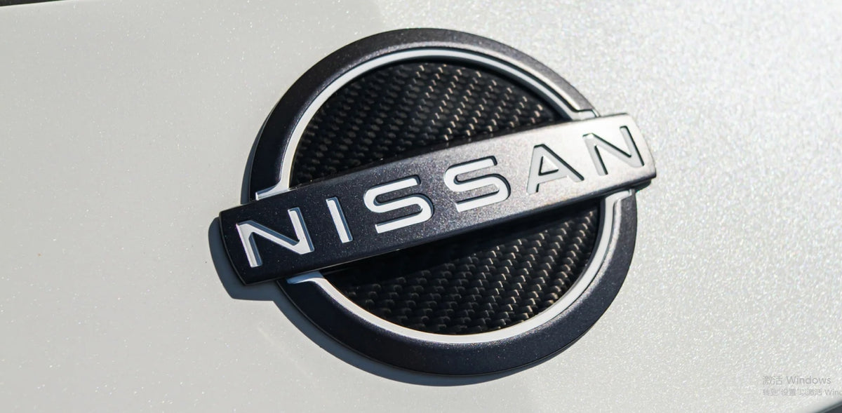Dry carbon fiber inserts installed inside a Nissan Z emblem; original emblem not included
